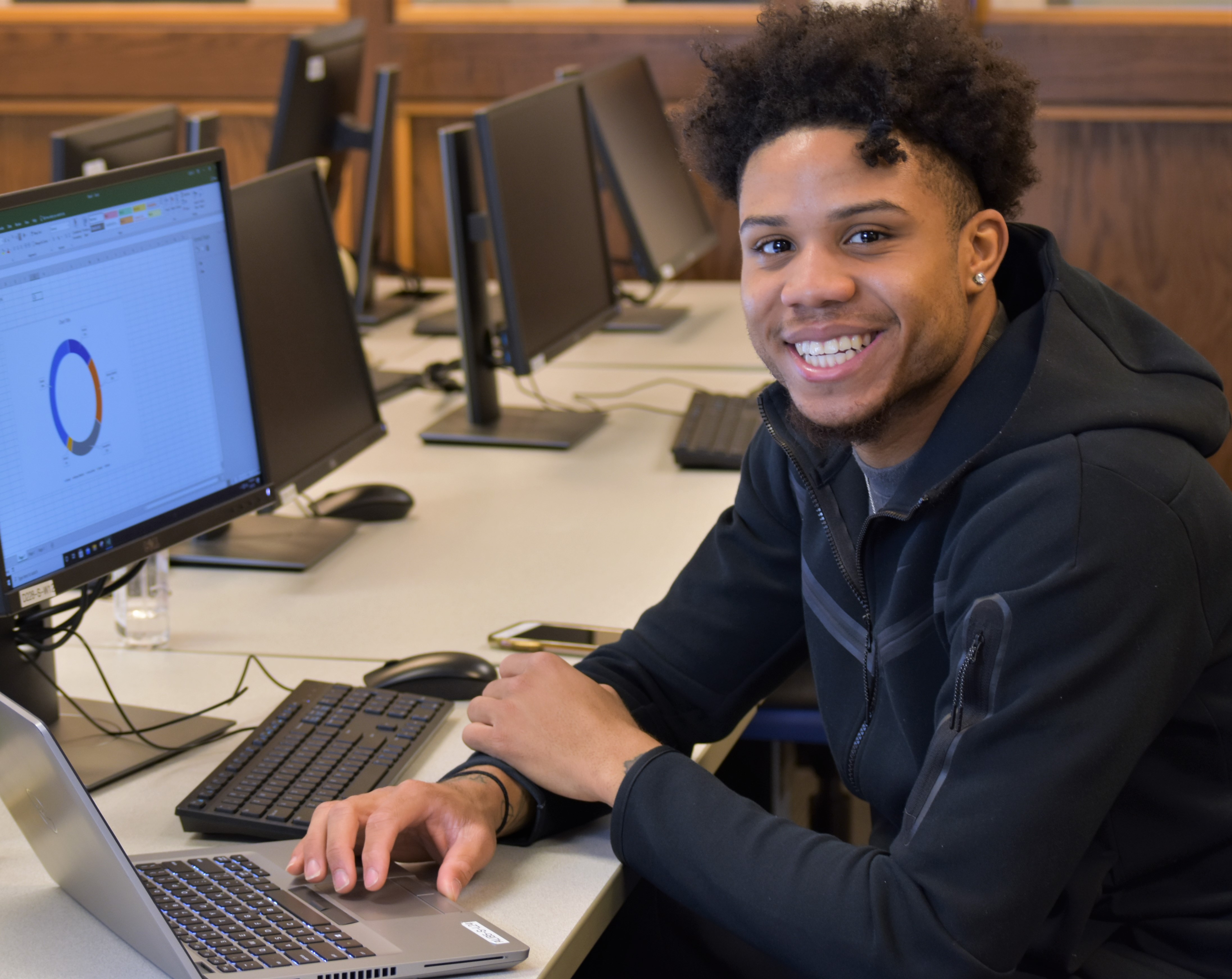 smiling african american student looking at graph on computer